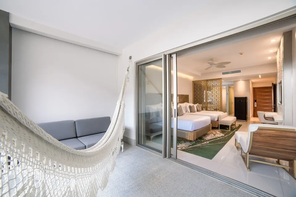 Junior Suite terrace with hammock, sofa, and open sliding doors to the king bed at Garza Blanca Los Cabos.