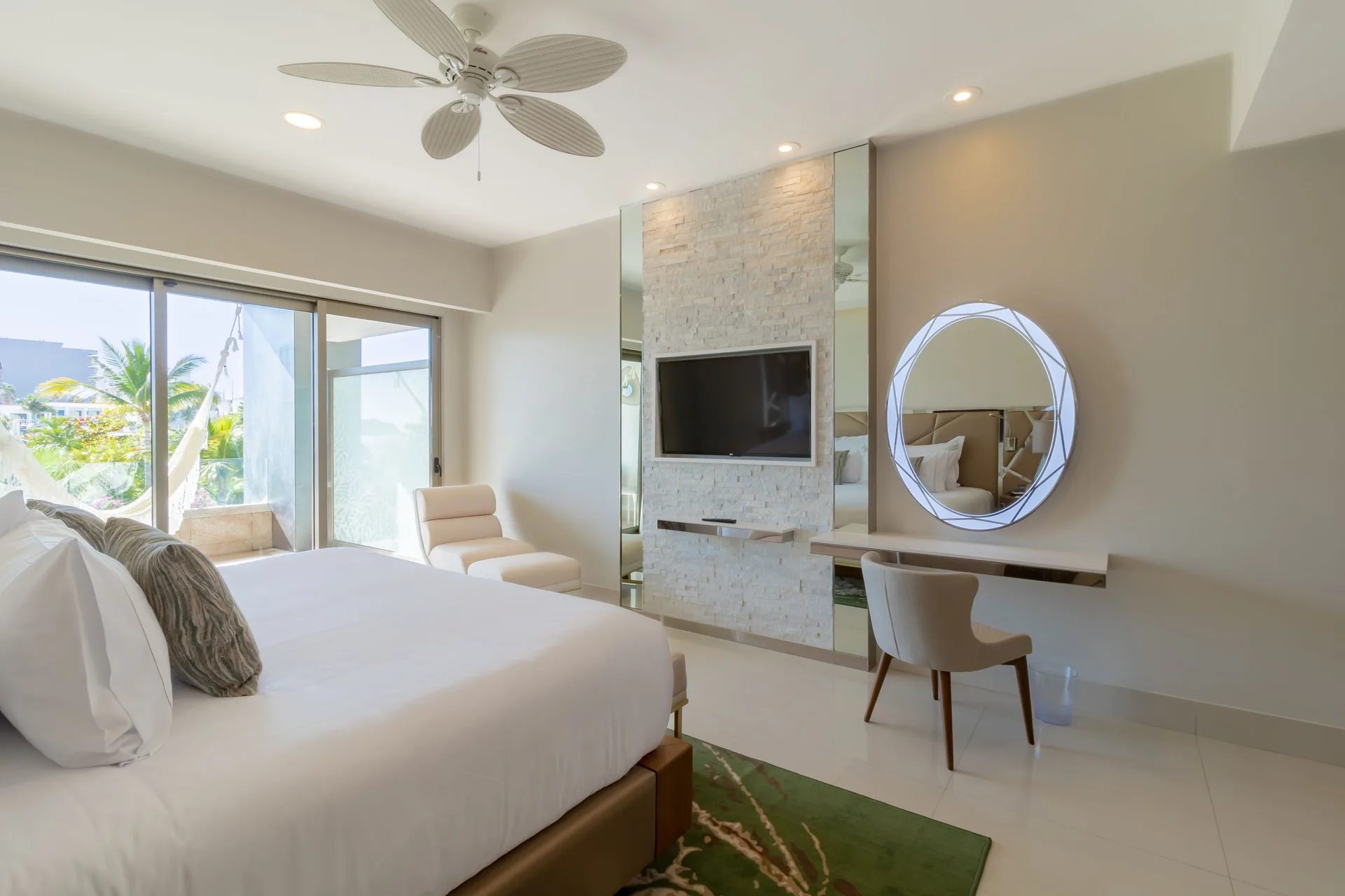 Junior Suite king bed, TV wall, desk, and balcony doors at Garza Blanca Los Cabos.