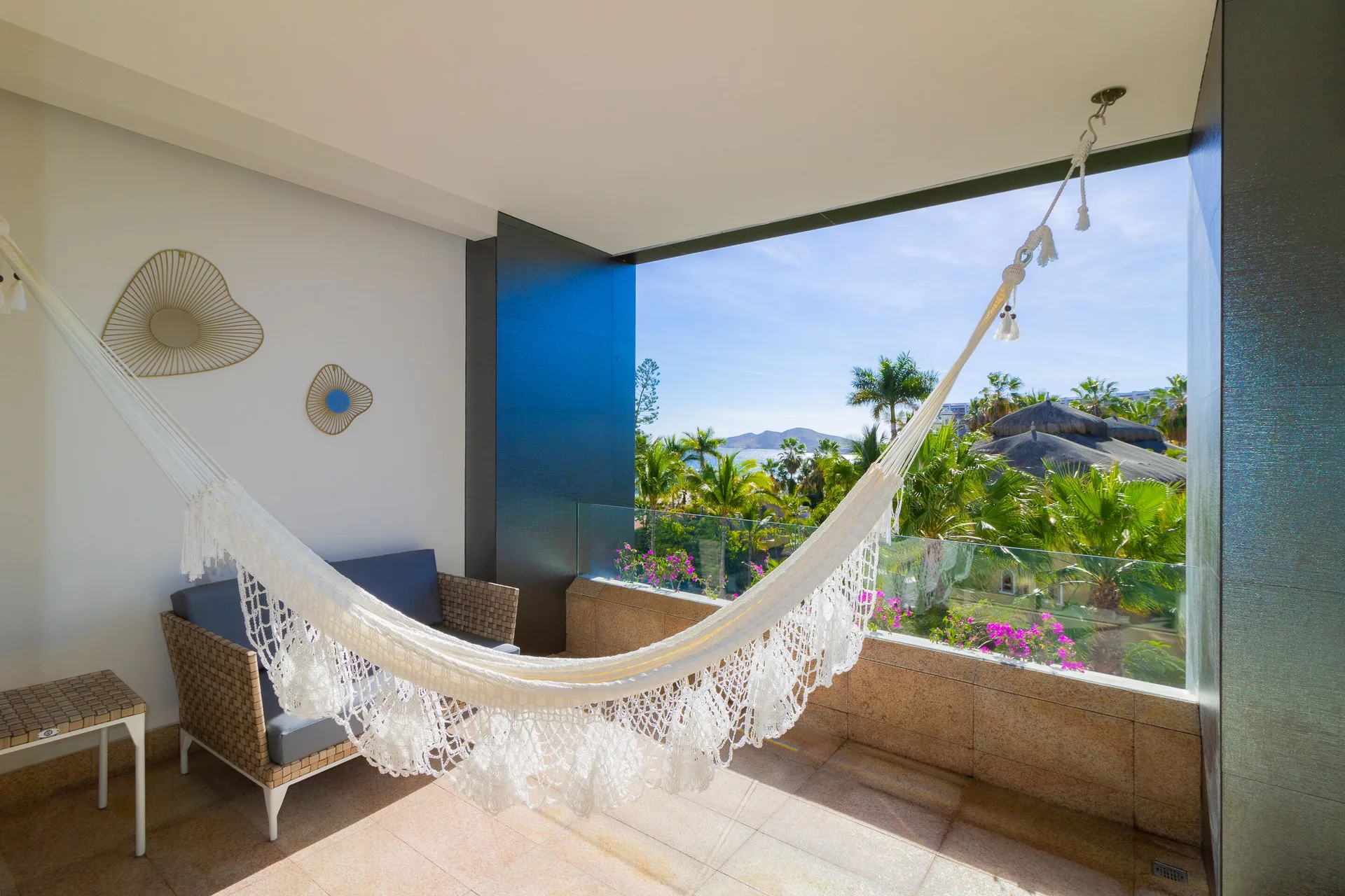 Junior Suite terrace hammock with seating, palms, and ocean in the distance at Garza Blanca Los Cabos.