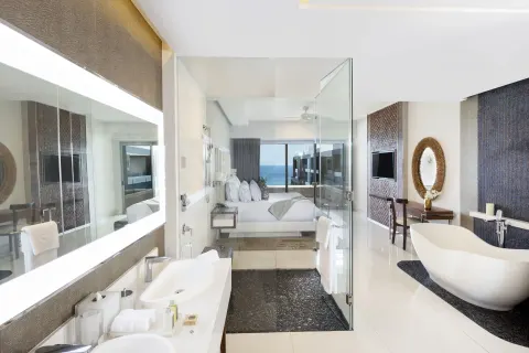 Loft Ocean View bathroom and king bed with ocean beyond at Garza Blanca Los Cabos.