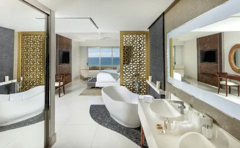 Bedroom and open bathroom with freestanding tub at Garza Blanca Los Cabos.