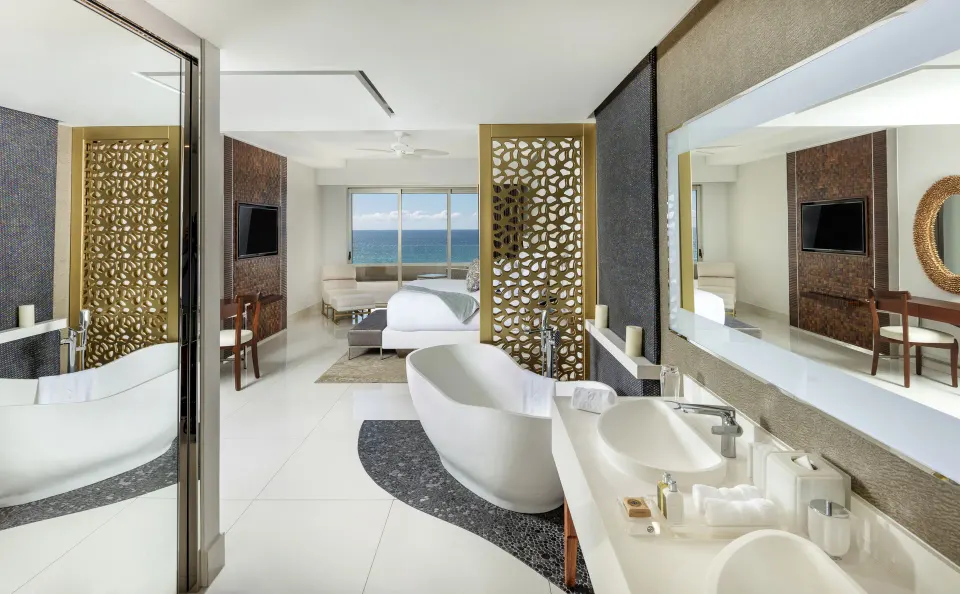 Bedroom and open bathroom with freestanding tub at Garza Blanca Los Cabos.