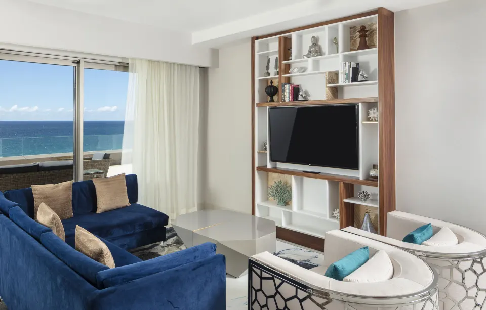 Living room with blue sectional and TV wall at Garza Blanca Los Cabos.