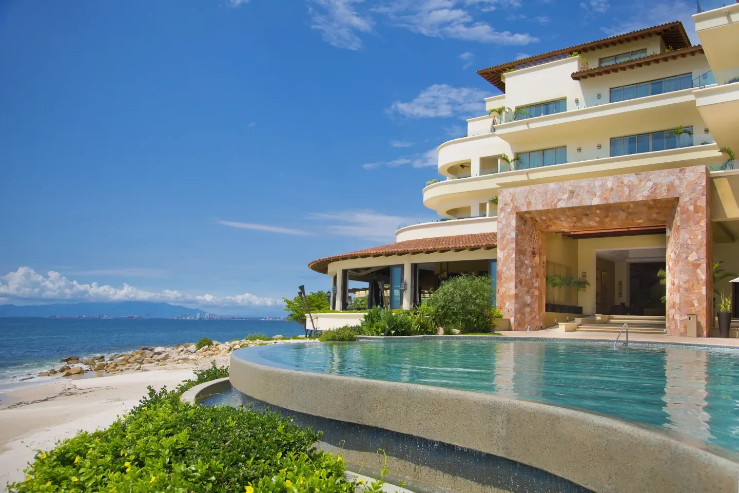 Beachfront pool and resort building at Garza Blanca Preserve Resort & Spa beside the ocean.