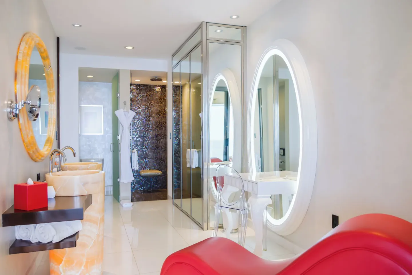 Bright guest bathroom with round mirrors and glass shower at Garza Blanca Preserve Resort & Spa.