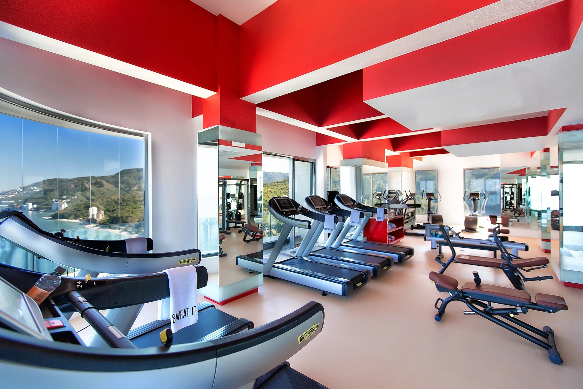 Gym with treadmills, benches, mirrors, and coastal views at Garza Blanca Preserve Resort & Spa.