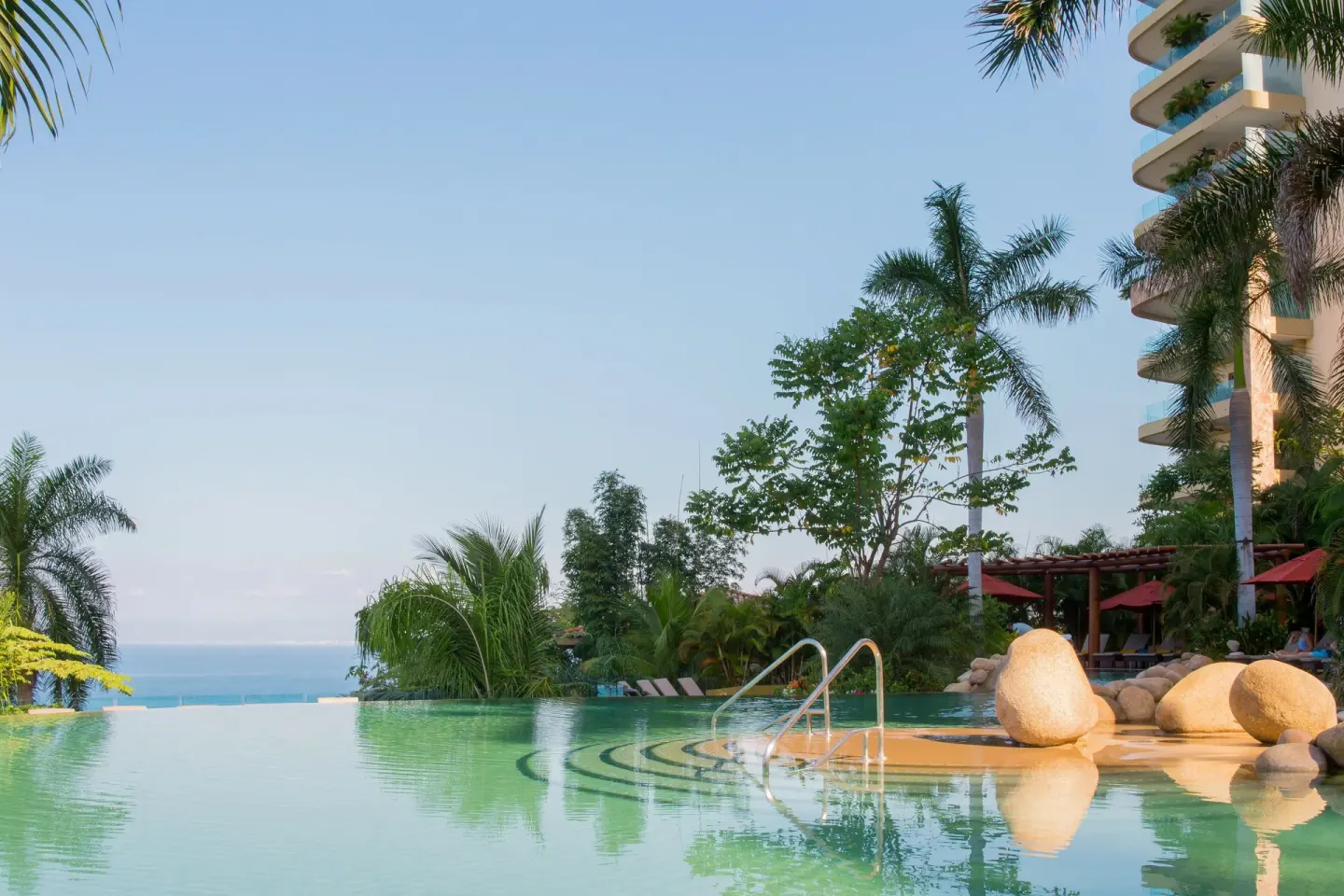 Infinity pool steps, rocks, palms, and ocean at Garza Blanca Preserve Resort & Spa.