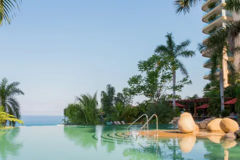 Infinity pool steps, rocks, palms, and ocean at Garza Blanca Preserve Resort & Spa.