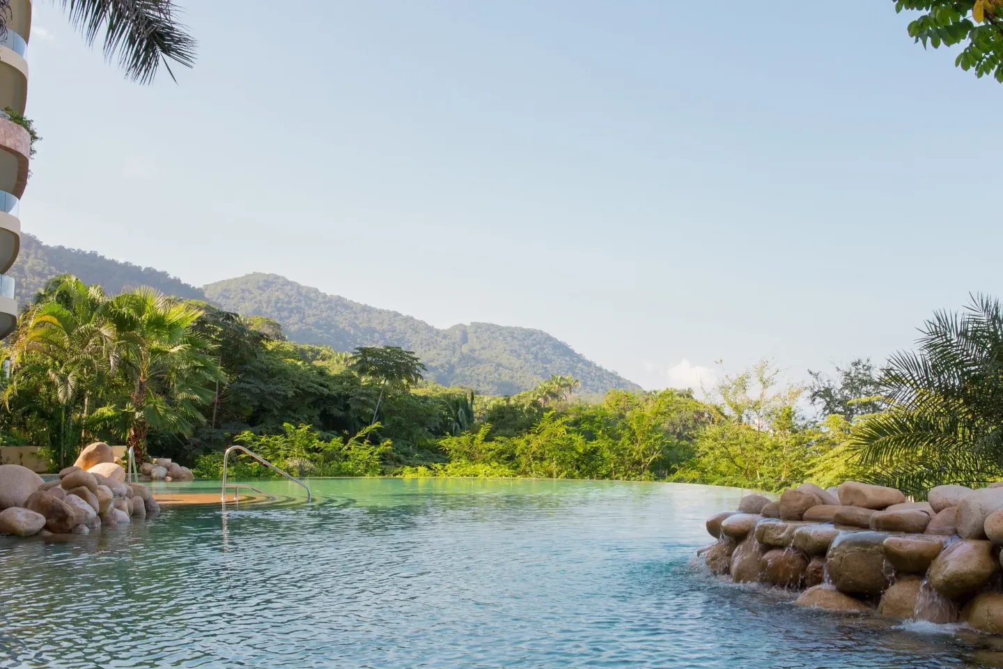 Infinity pool with rock features and mountain greenery at Garza Blanca Preserve Resort & Spa.