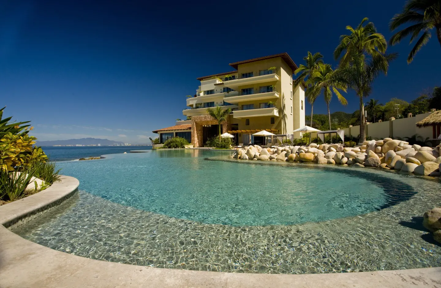 Resort pool facing the ocean and a yellow building at Garza Blanca Preserve Resort & Spa.