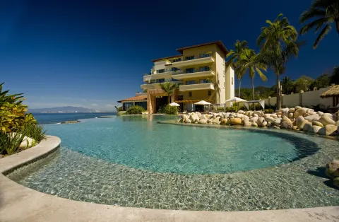 Resort pool facing the ocean and a yellow building at Garza Blanca Preserve Resort & Spa.