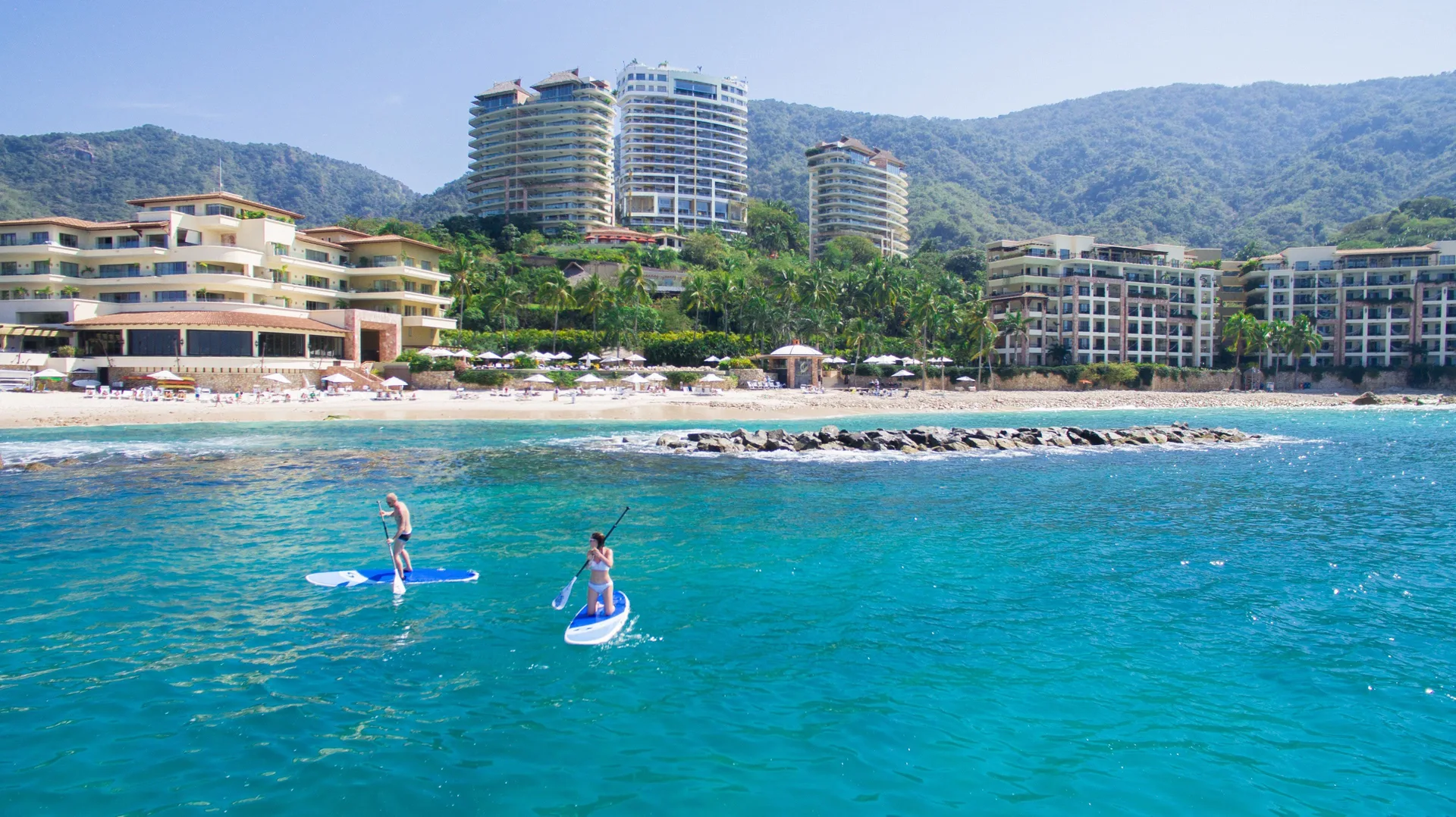 Paddleboarders on turquoise water off Garza Blanca Preserve Resort & Spa.