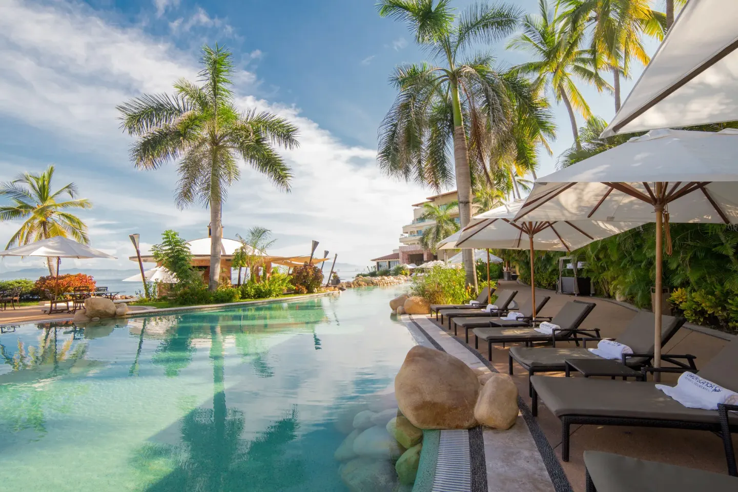 Palm-lined pool with loungers and umbrellas at Garza Blanca Preserve Resort & Spa.