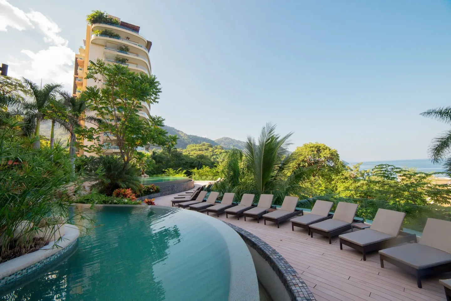 Pool deck with lounge chairs, greenery, and ocean beyond at Garza Blanca Preserve Resort & Spa.