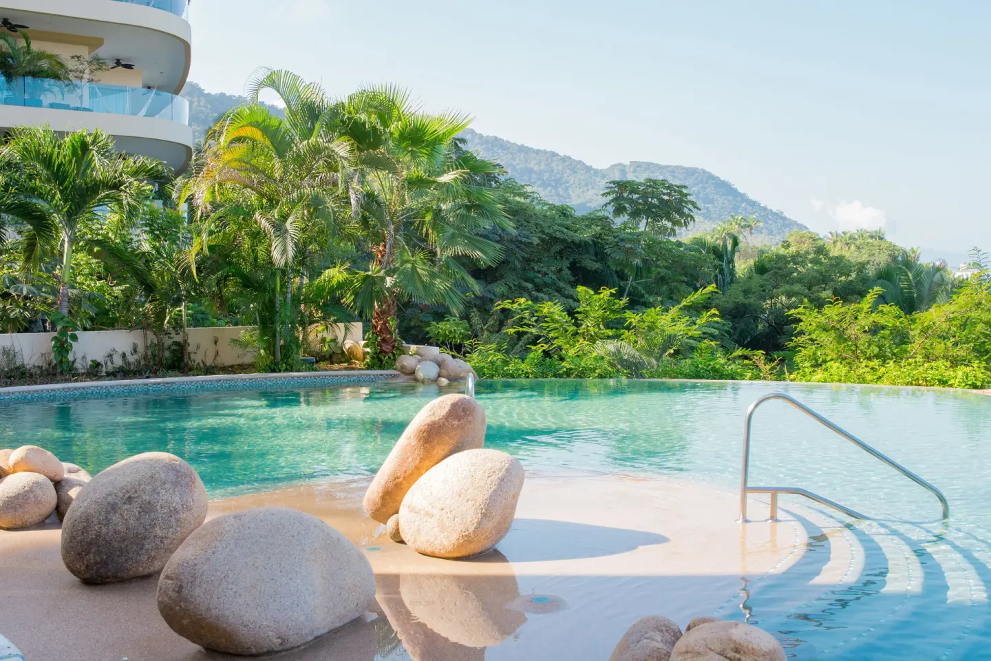 Pool terrace with boulders, palms, and mountain greenery at Garza Blanca Preserve Resort & Spa.