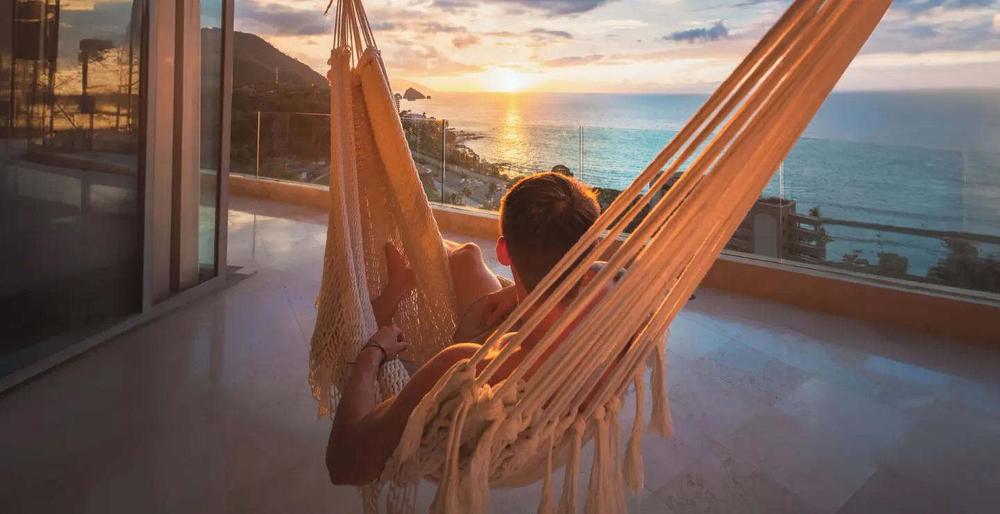 Guest relaxing in a balcony hammock at sunset at Garza Blanca Preserve Resort & Spa.