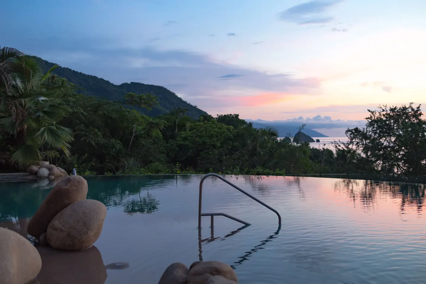 Sunset over an infinity pool and forested hills at Garza Blanca Preserve Resort & Spa.