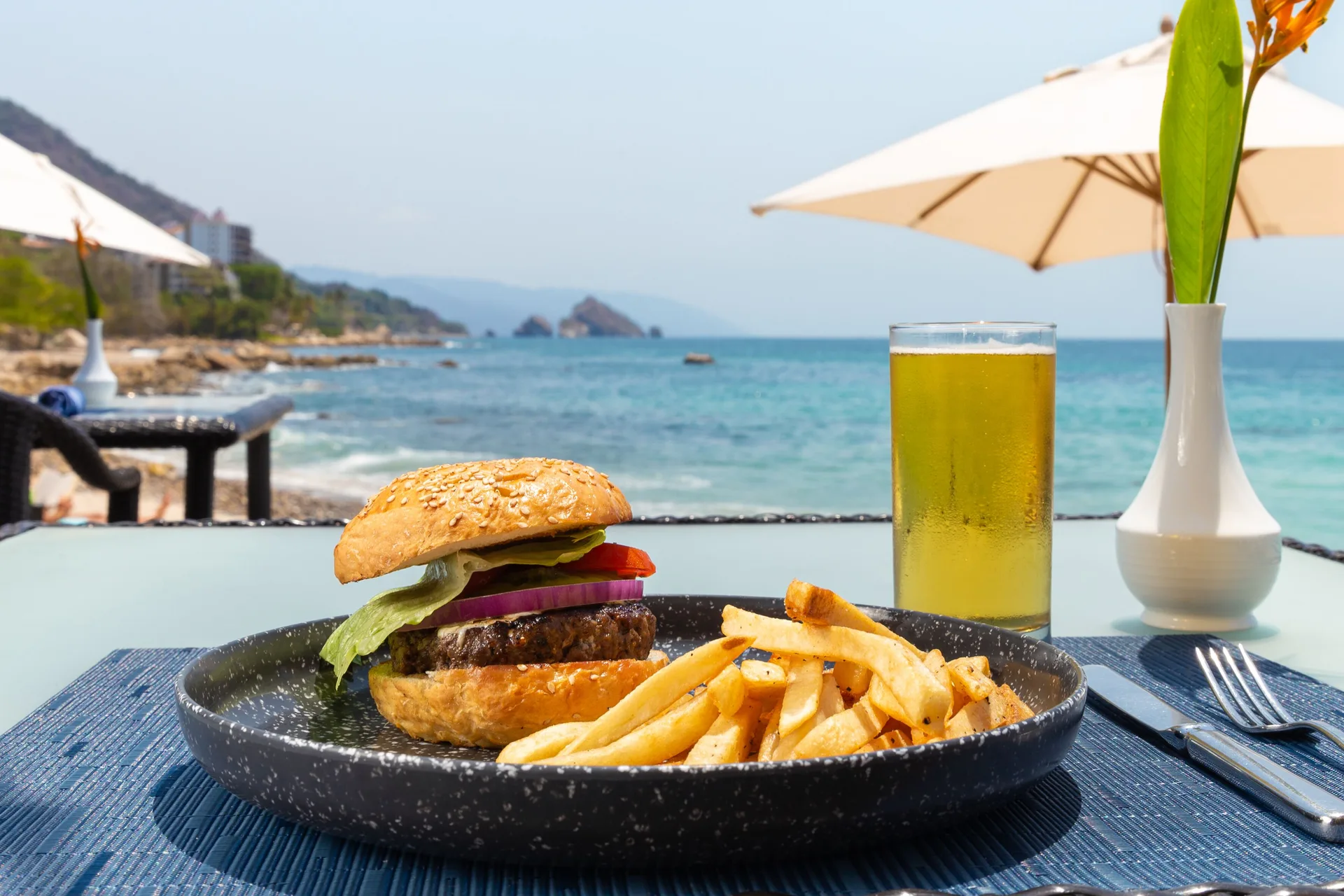 Burger, fries, and beer on an ocean-view table at Garza Blanca Preserve Resort & Spa.