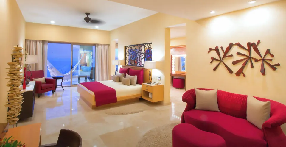 Junior Panoramic Suite king bed and red lounge seating at Garza Blanca Preserve Resort & Spa.