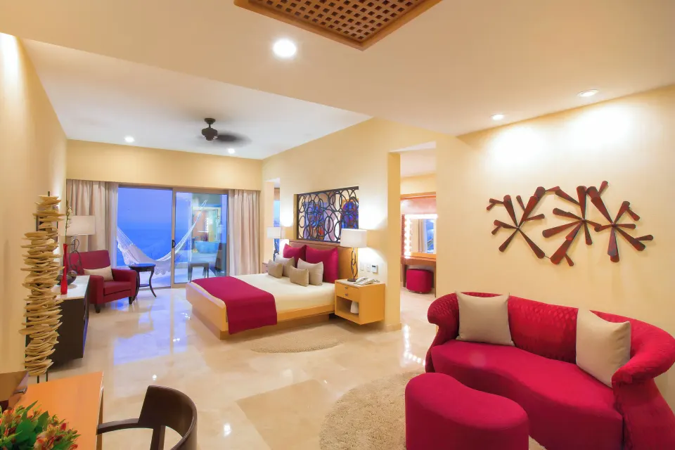 Junior Panoramic Suite king bed, sofa, and balcony doors at Garza Blanca Preserve Resort & Spa.