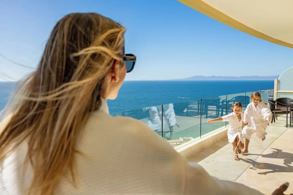 Junior Panoramic Suite terrace with ocean view and family in robes at Garza Blanca Preserve Resort & Spa.