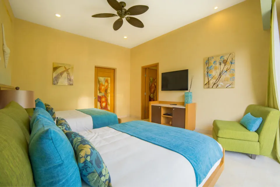 One Bedroom Suite twin beds with turquoise accents at Garza Blanca Preserve Resort & Spa.