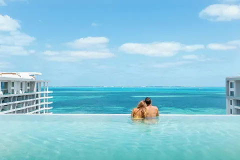 Couple sitting at the infinity pool edge at Garza Blanca Resort & Spa Cancun.