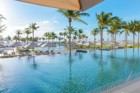 Infinity pool with palms, loungers, and umbrellas at Garza Blanca Resort & Spa Cancun.