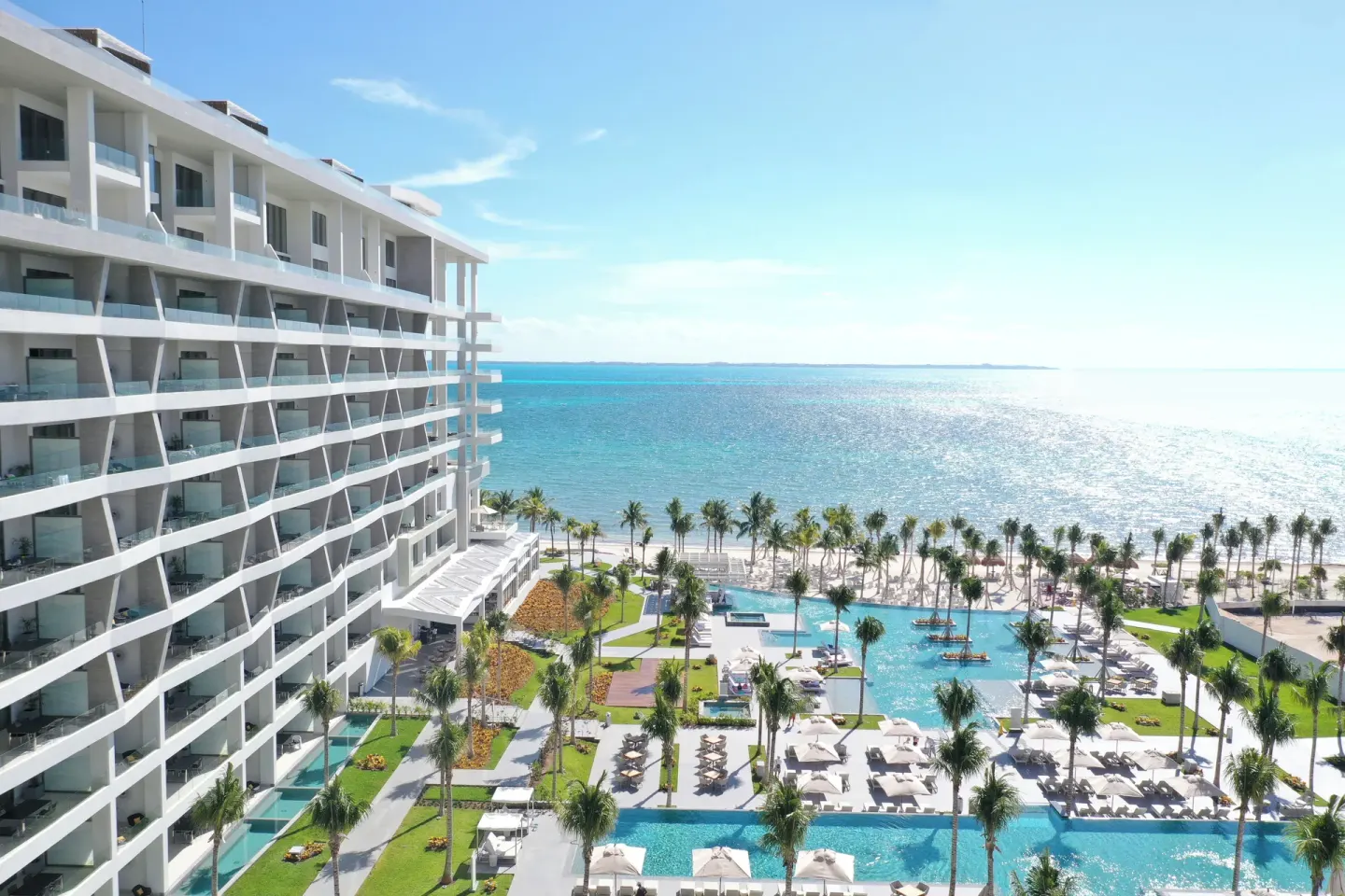 An ocean-facing resort tower, pools, palms, and beach at Garza Blanca Resort & Spa Cancun.