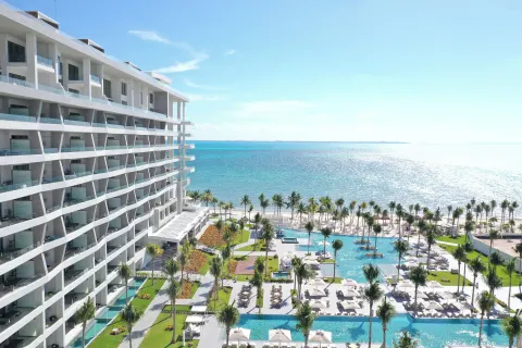 An ocean-facing resort tower, pools, palms, and beach at Garza Blanca Resort & Spa Cancun.
