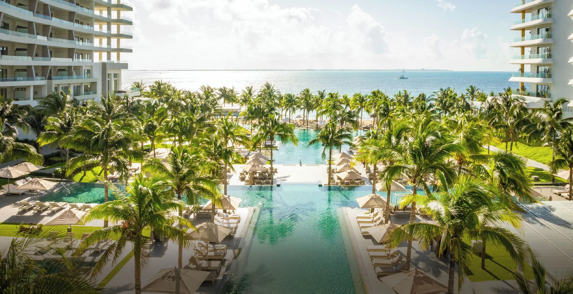 Palm-lined pools between resort towers and the sea at Garza Blanca Resort & Spa Cancun.
