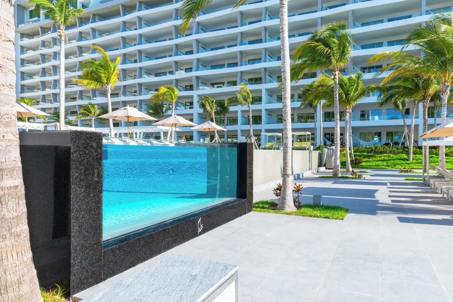 Pool deck with glass-sided pool and resort balconies at Garza Blanca Resort & Spa Cancun.