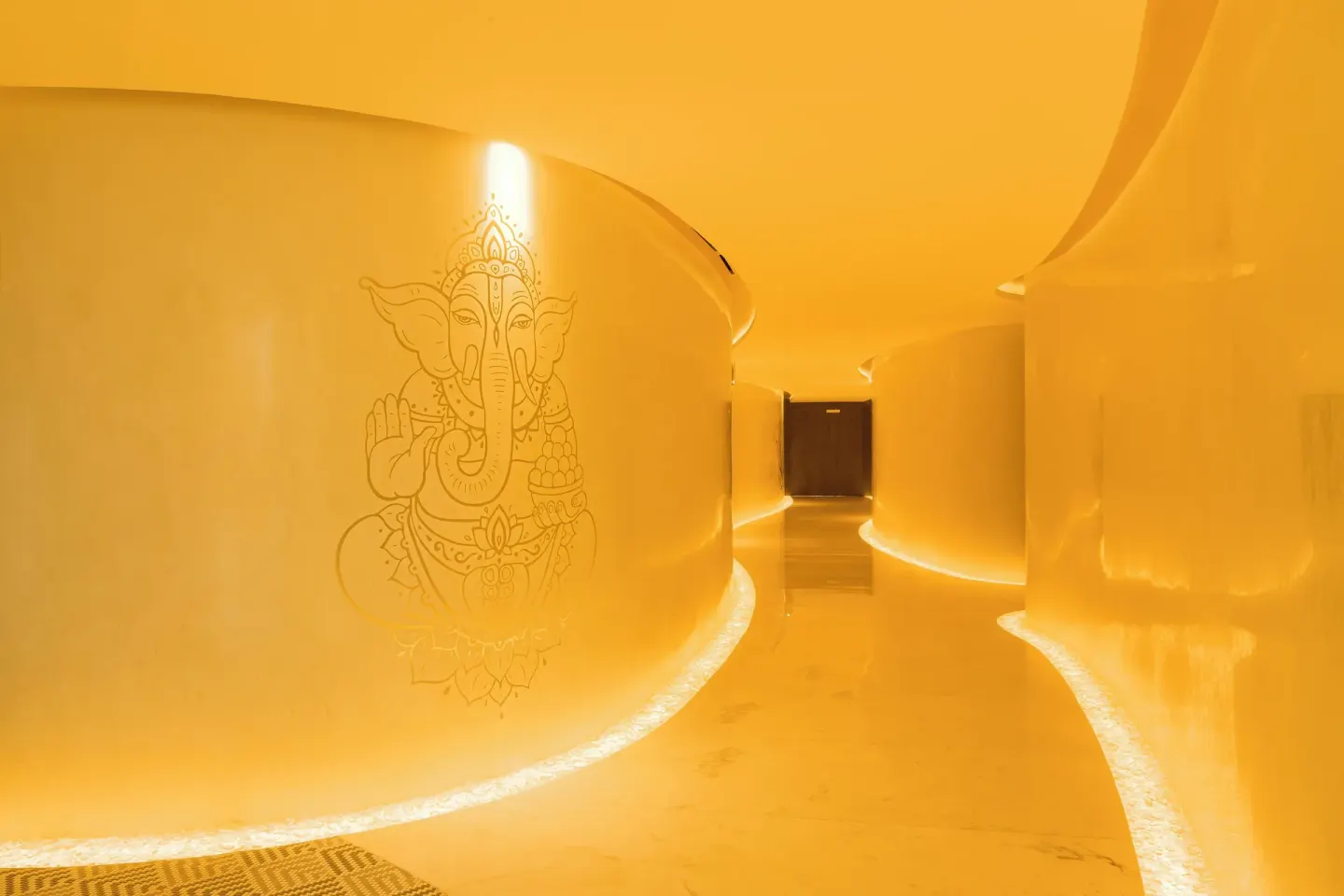 Warm yellow spa corridor with curved walls at Garza Blanca Resort & Spa Cancun.