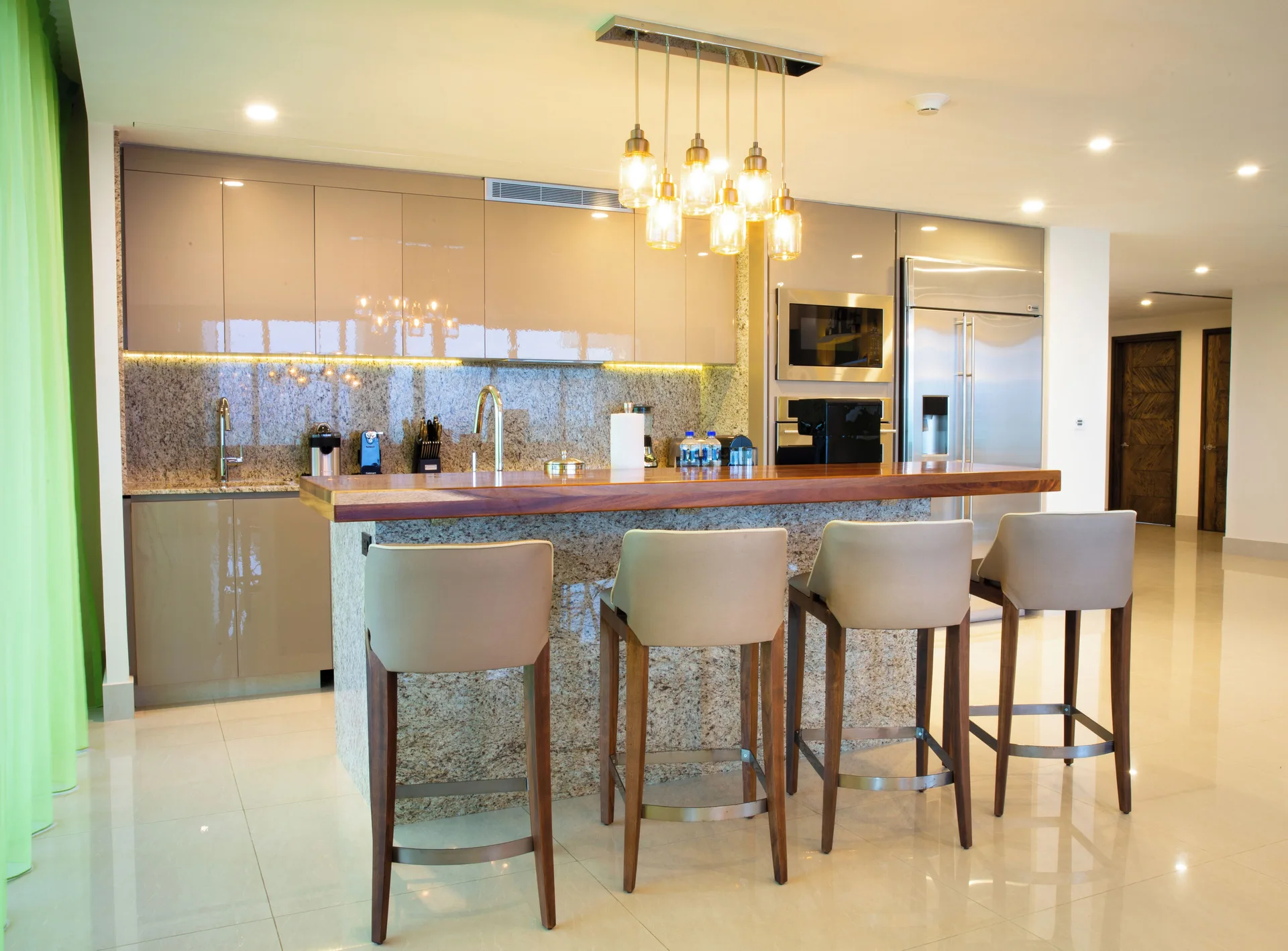 Suite kitchen island with bar stools and appliances at Garza Blanca Resort & Spa Cancun.