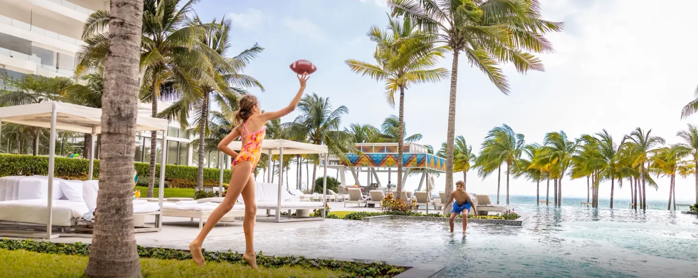 Wide poolside scene with children playing football at Garza Blanca Resort & Spa Cancun.