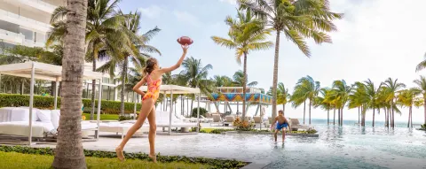 Wide poolside scene with children playing football at Garza Blanca Resort & Spa Cancun.