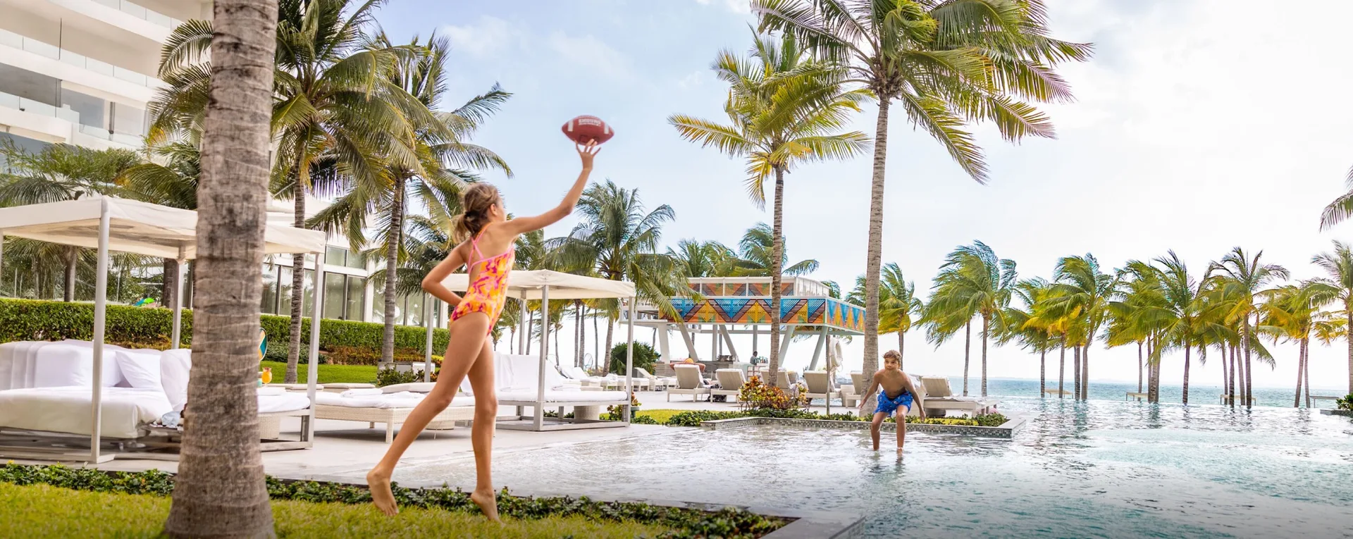 Wide poolside scene with children playing football at Garza Blanca Resort & Spa Cancun.