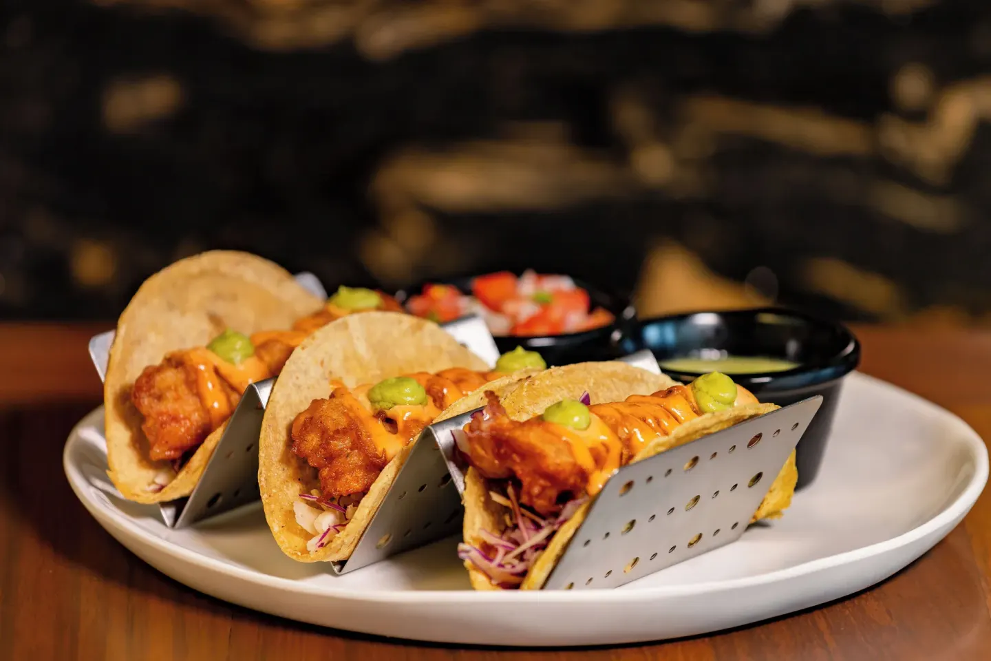 Three tacos with sauces are plated on a table at Garza Blanca Resort & Spa Cancun.