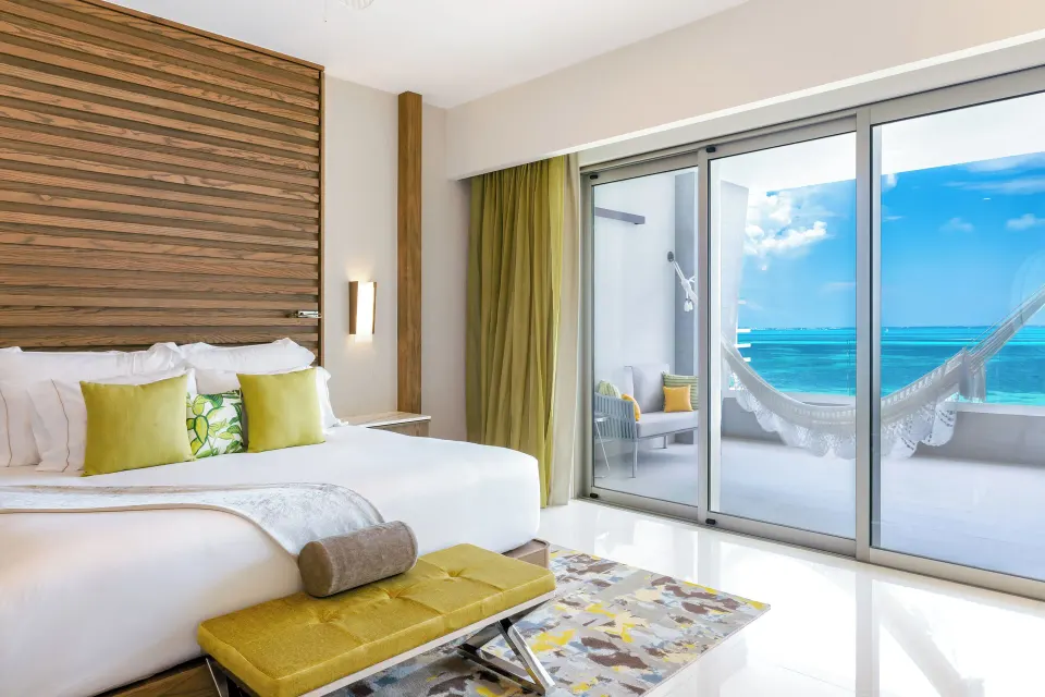 Junior Suite Ocean View king bed beside balcony doors at Garza Blanca Resort & Spa Cancun.