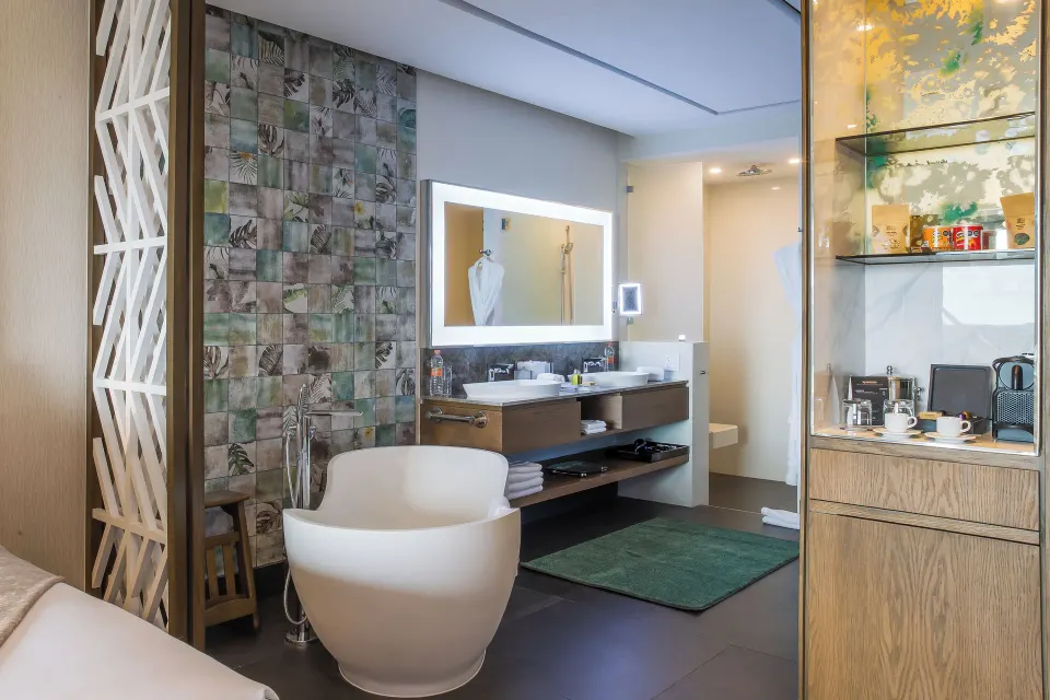 Junior Suite bathroom with freestanding tub and refreshment cabinet at Garza Blanca Resort & Spa Cancun.