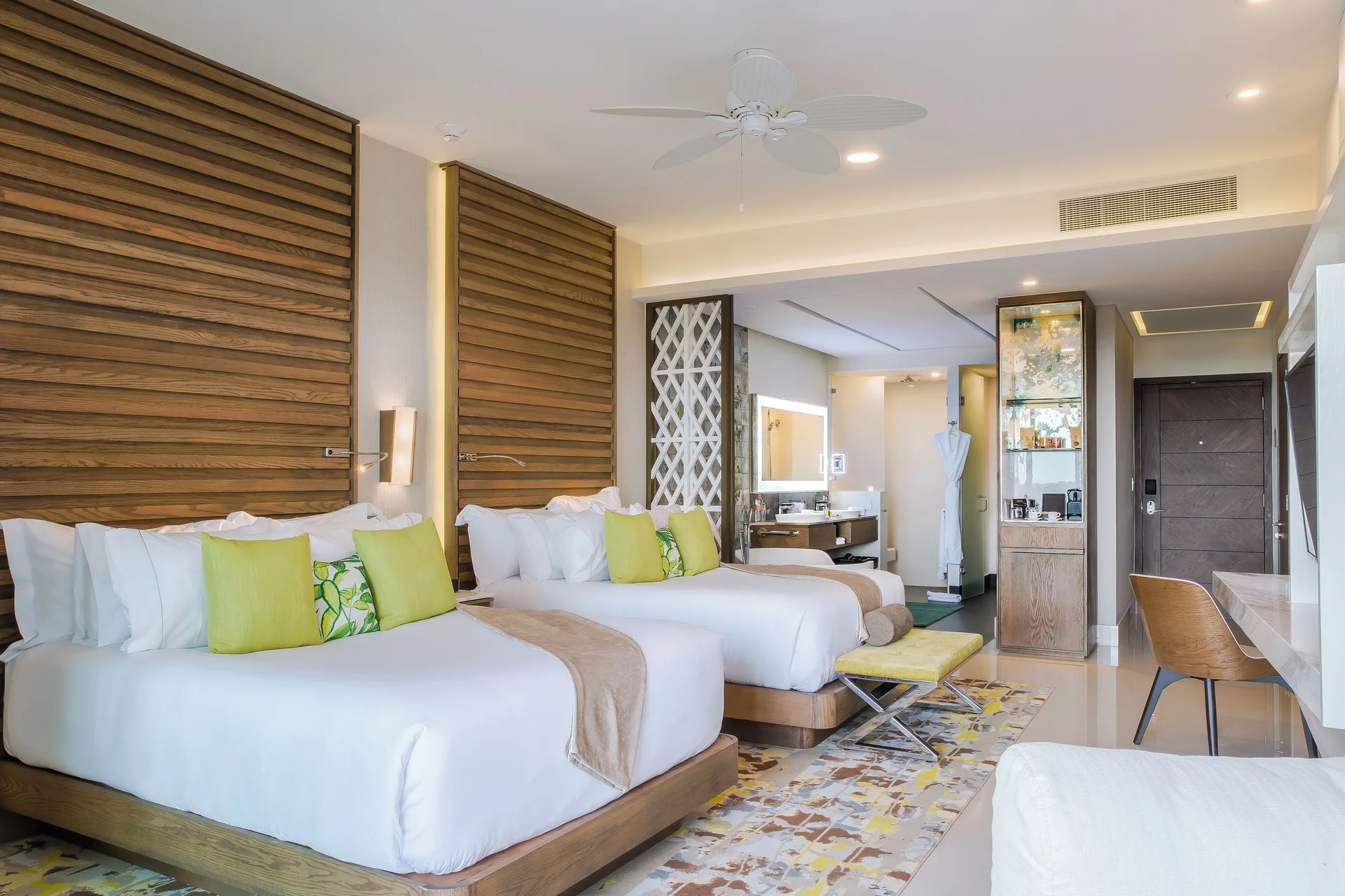 Junior Suite with two beds, wood headboards, desk, and open bath area at Garza Blanca Resort & Spa Cancun.