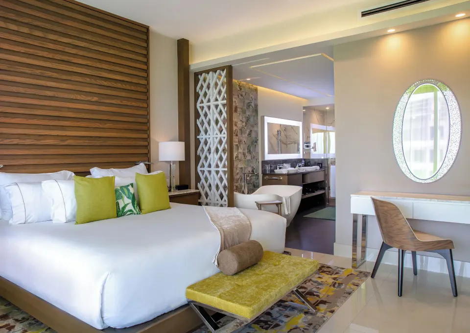 One Bedroom Suite king bed, desk, and bathroom vanity at Garza Blanca Resort & Spa Cancun.