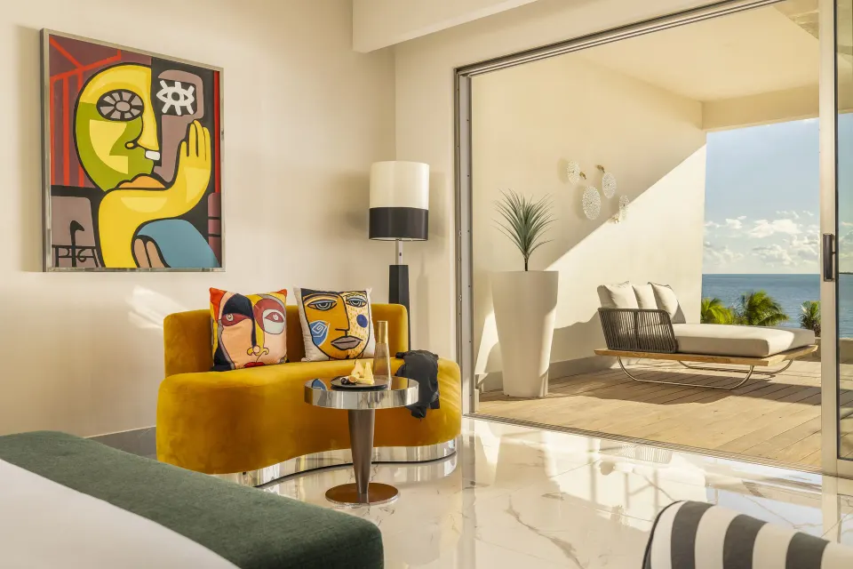 Oceanfront guest room sitting area with balcony at Garza Blanca Resort & Spa Cancun.