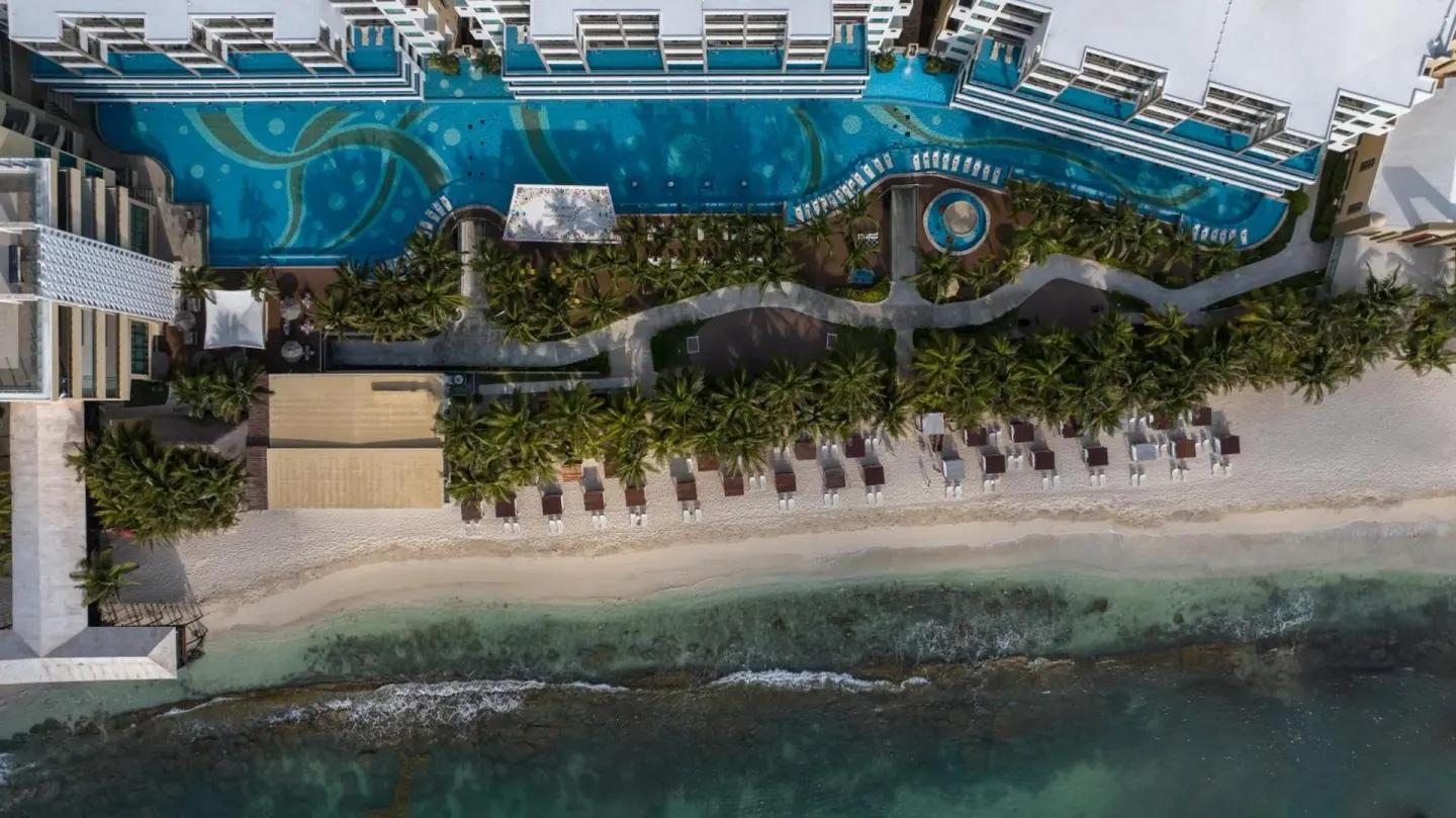 Aerial view of the beachfront pool, palms, loungers, and shoreline at Generations Riviera Maya.