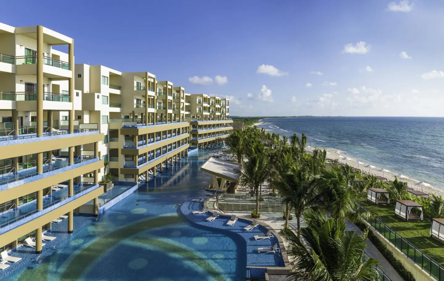 Beachfront resort buildings, pools, palms, and sea at Generations Riviera Maya.