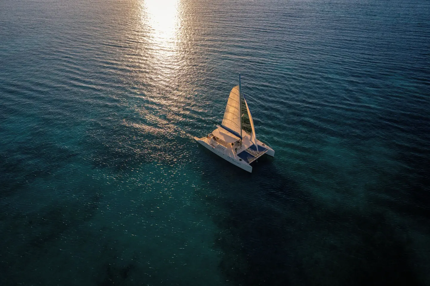 Catamaran sailing on sunlit ocean water near Generations Riviera Maya.