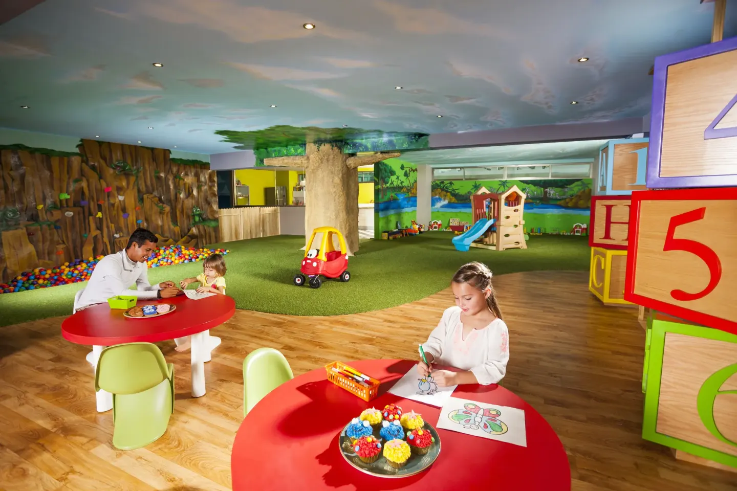 Children color at red tables in a playroom at Generations Riviera Maya.