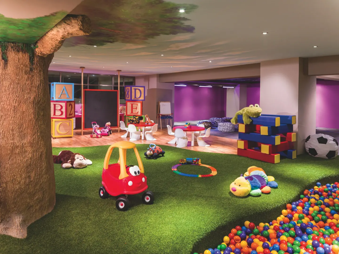 Children's playroom with toys, ball pit, and faux tree at Generations Riviera Maya.