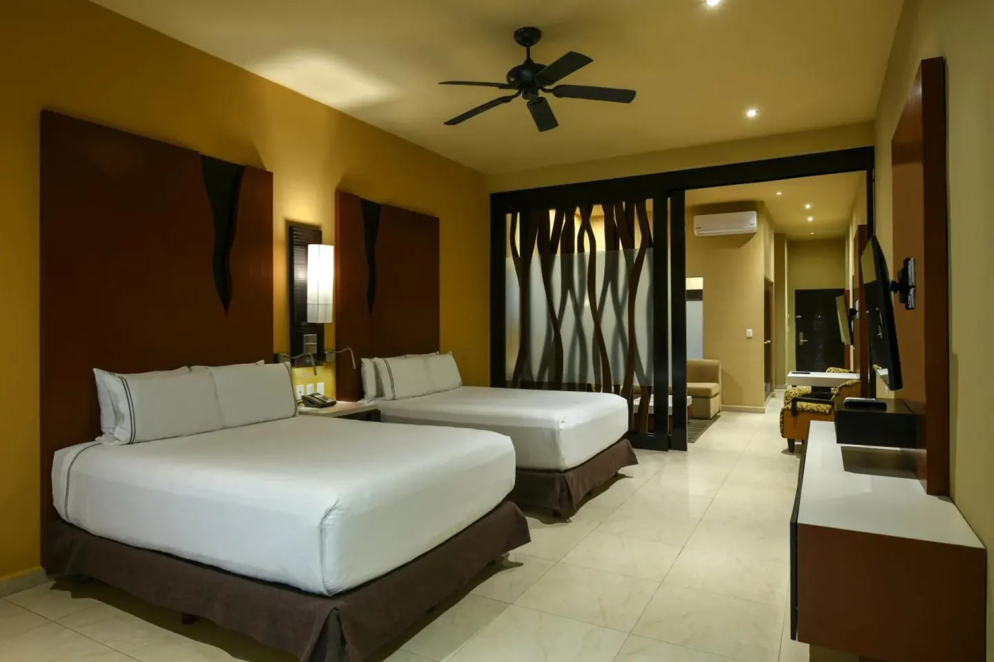 Guest room with two double beds and warm wood accents at Generations Riviera Maya.