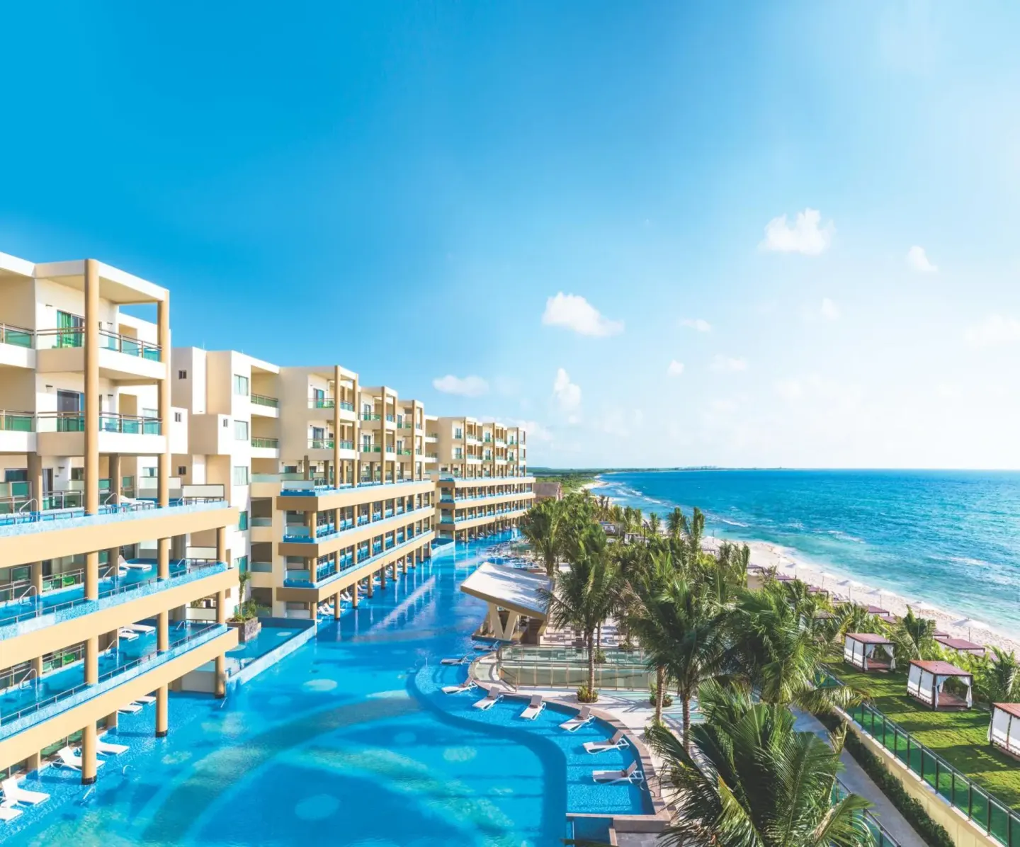 Oceanfront resort buildings, pool decks, palms, and beach at Generations Riviera Maya.